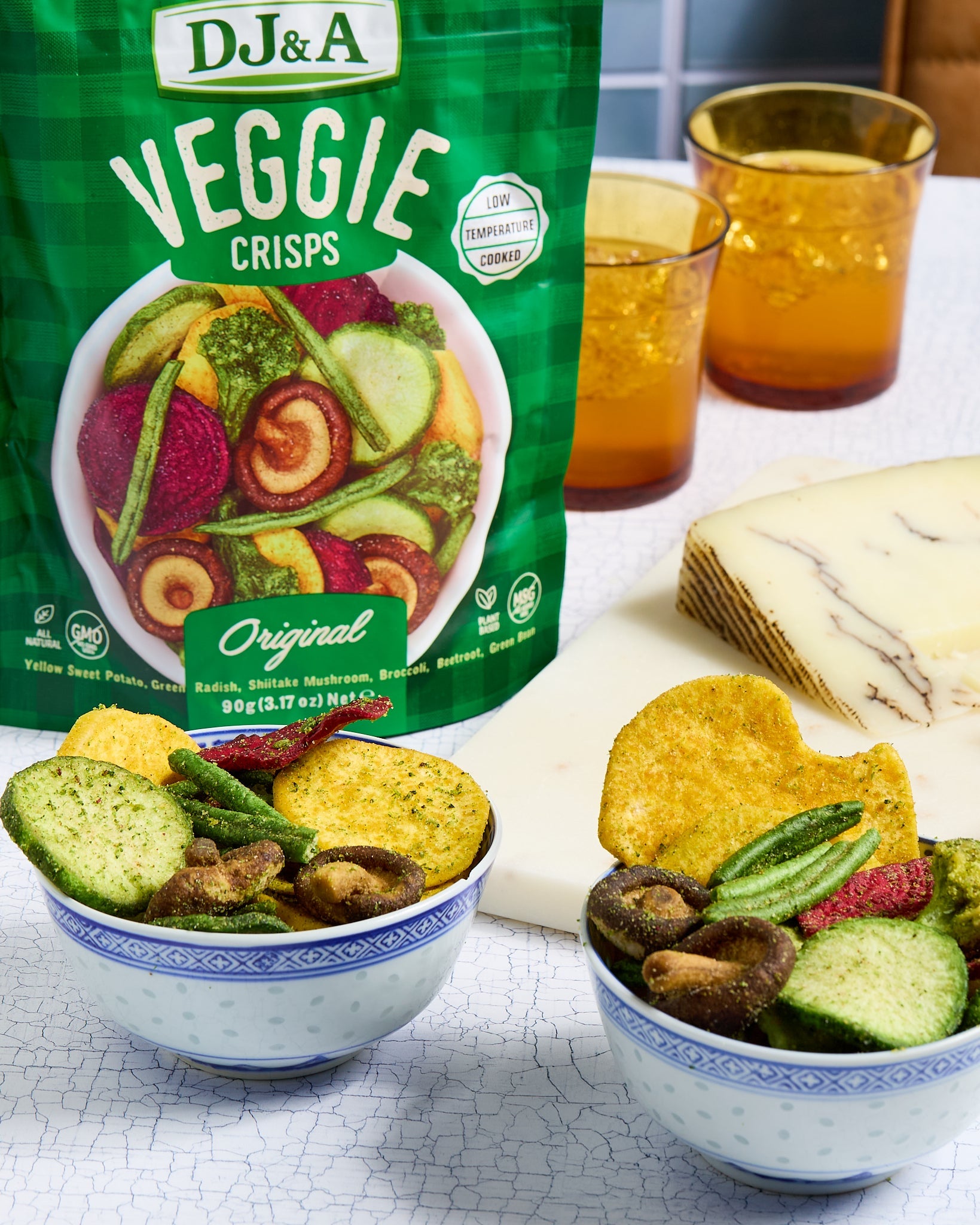 Packaging of DJ&A Veggie Crisps with bowls of crisps on a table.